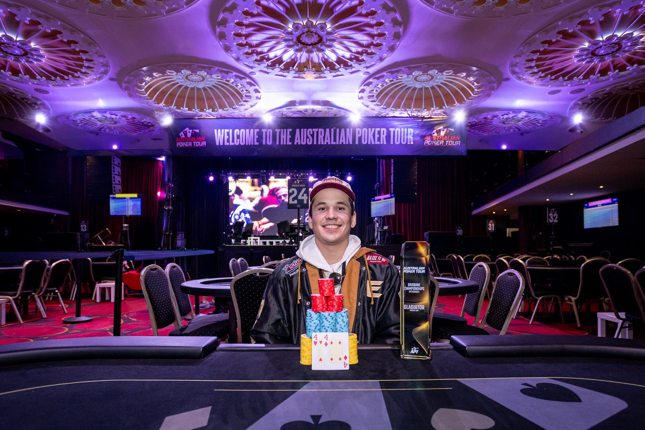 Poker tournament champion with trophy on stage in a ballroom · Jamie Hall, Definitive Imaging