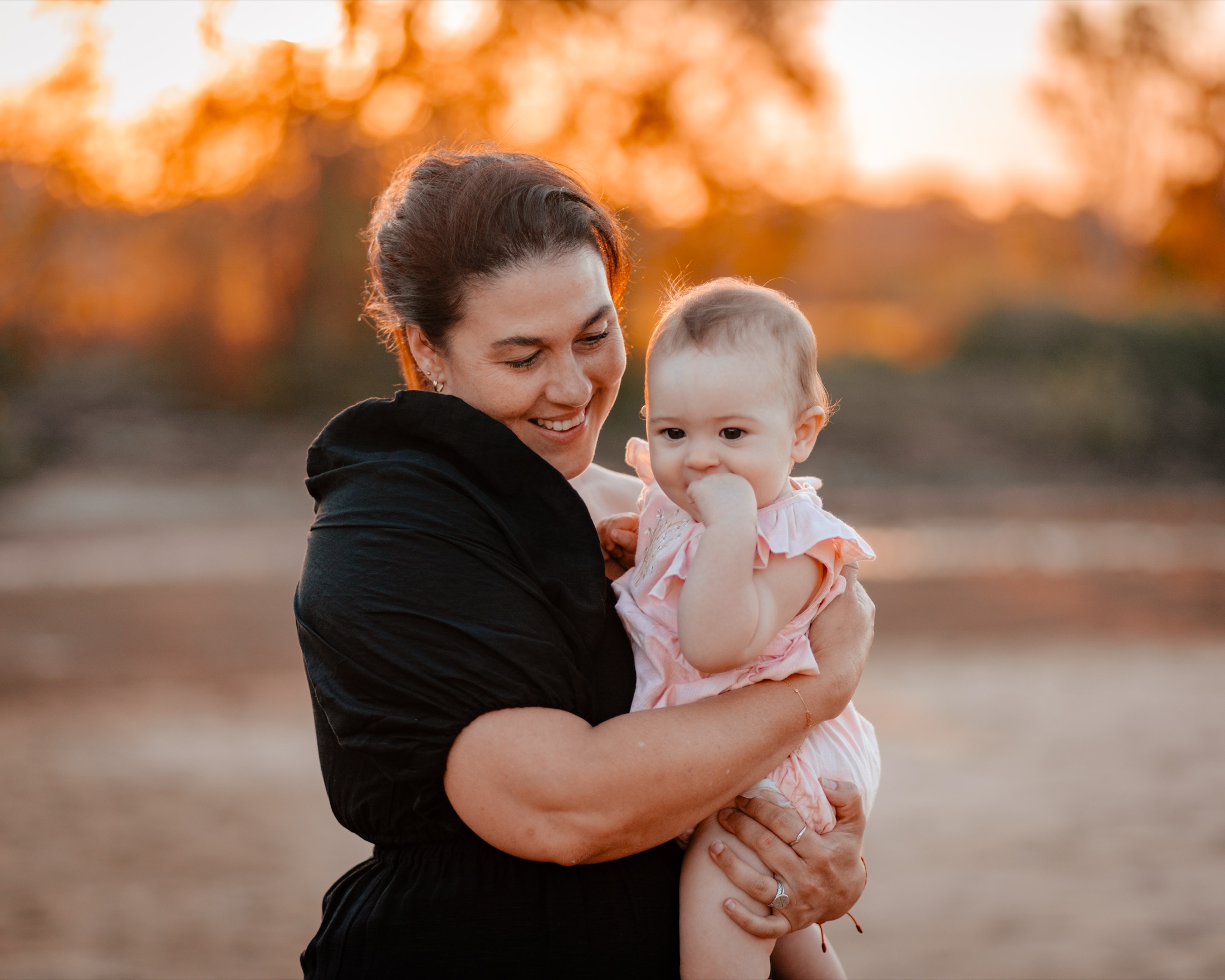 Mother holding her baby daughter in warm sunset light · Jamie Hall, Definitive Imaging